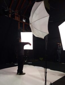 a man stands in a photo studio facing bright lights as he poses for a picture