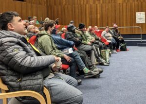 A side view of an audience of disabled people sitting in an auditorium