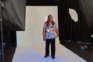 a woman stands for a photo against a white background with flash umbrellas set up to either side